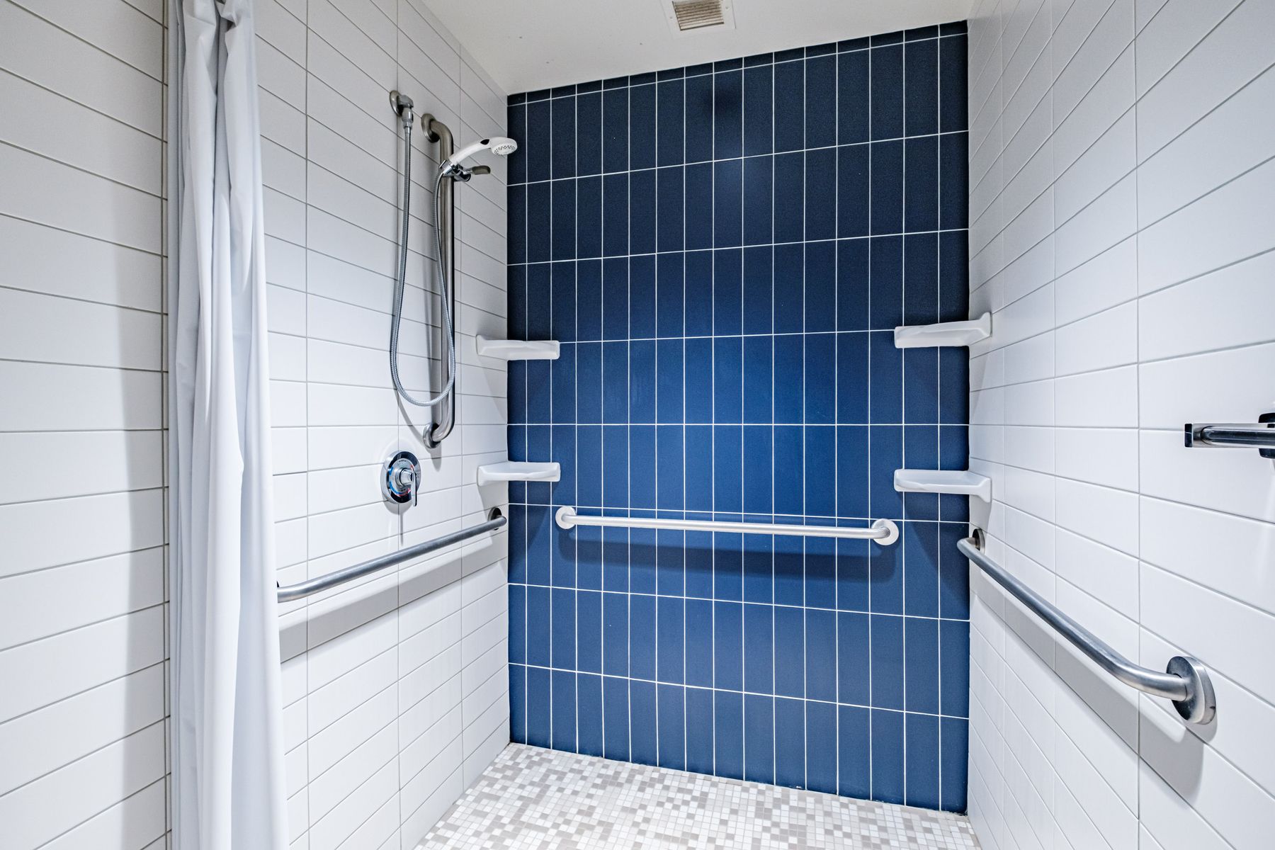 Walk-in luxury shower with blue tile and grab rails